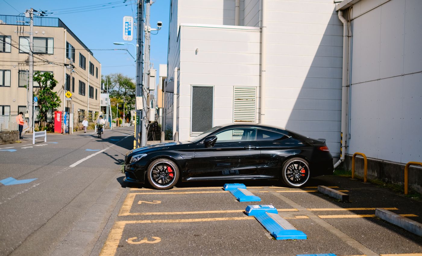 A black sports coupe parked beside a building on a sunny urban street