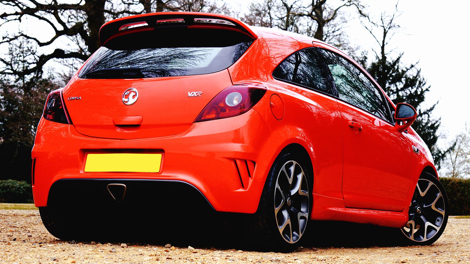 A red Vauxhall Corsa VXR parked outdoors beneath trees