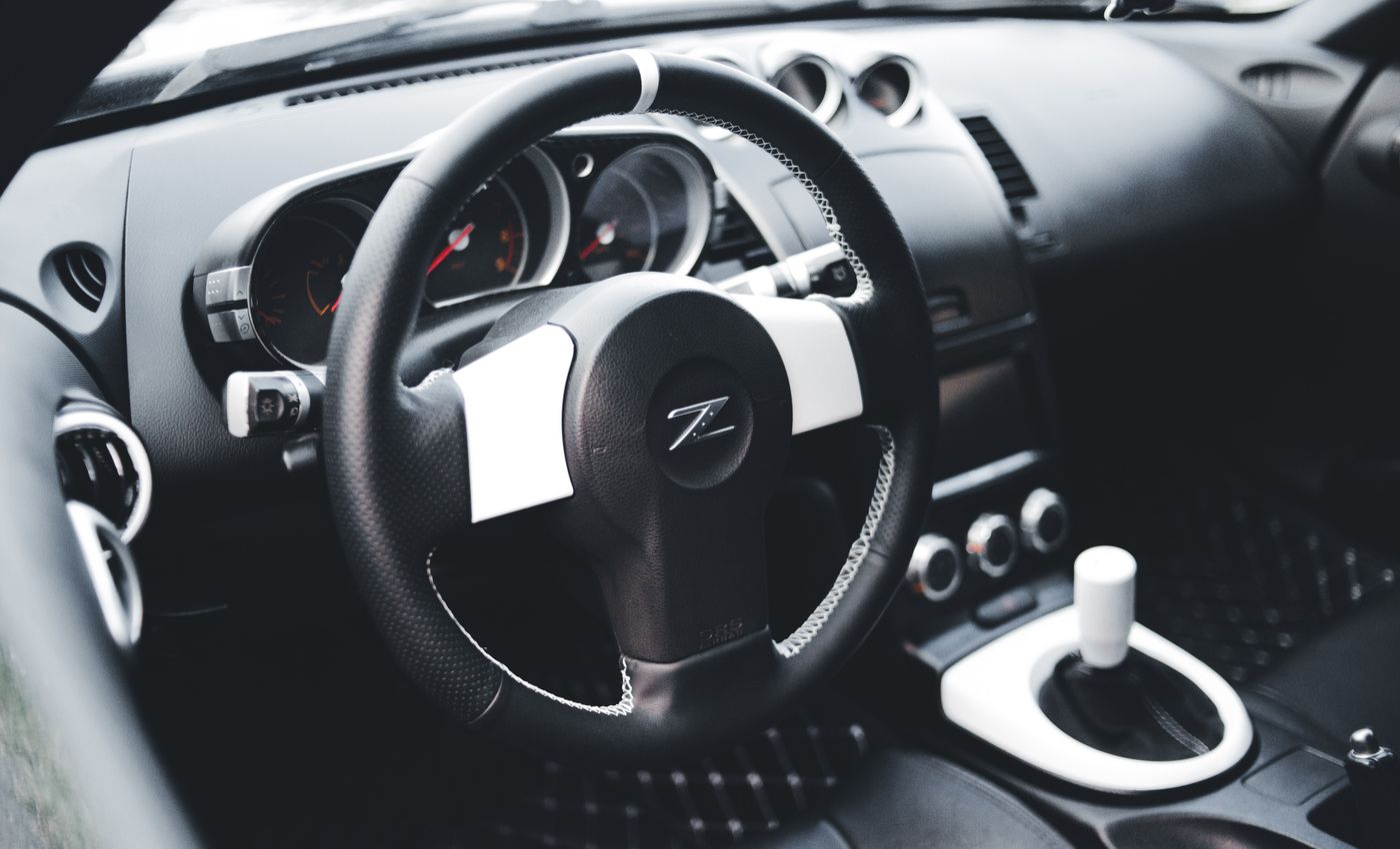 A close view of a Nissan sports car’s steering wheel, dashboard and manual gear lever