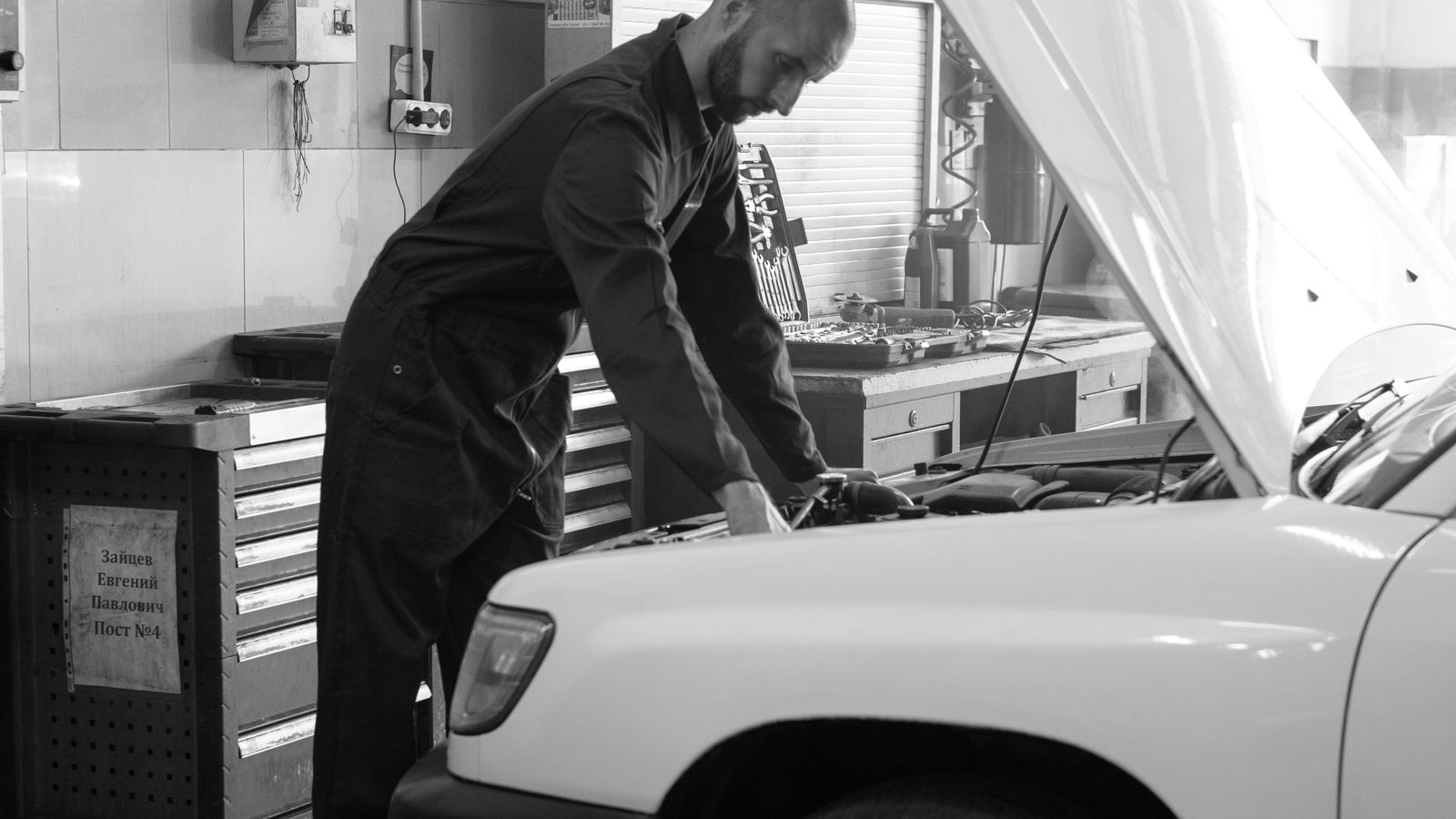 A mechanic examining a car engine in a workshop