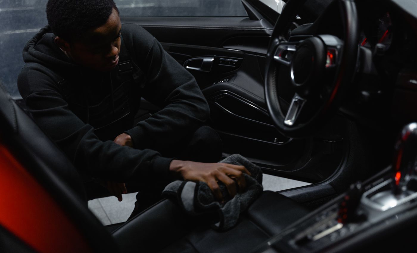 A person carefully cleaning a car’s interior before sale
