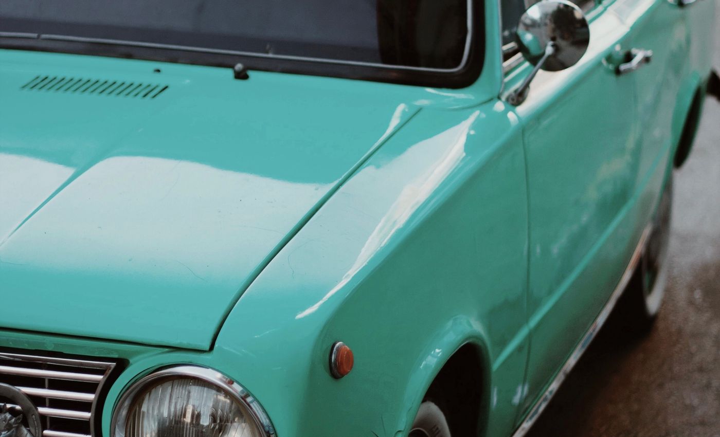 The bonnet and headlight of a mint-green classic car